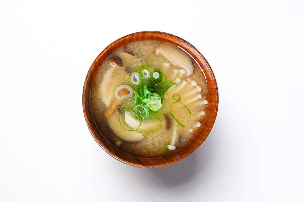 Mushroom miso soup in a wooden bowl and topped with chopped spring onions
