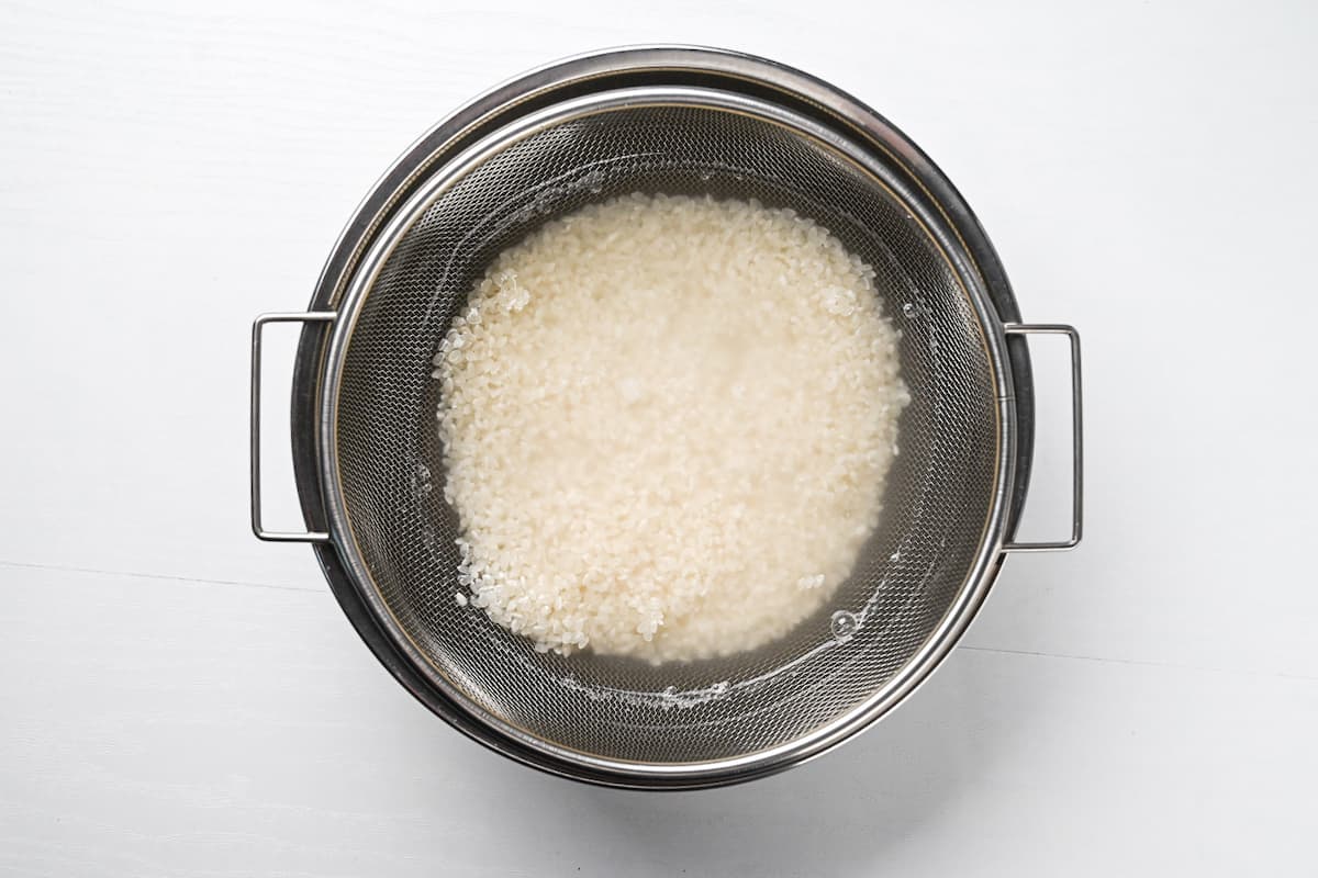 Washing rice in a sieve over a bowl