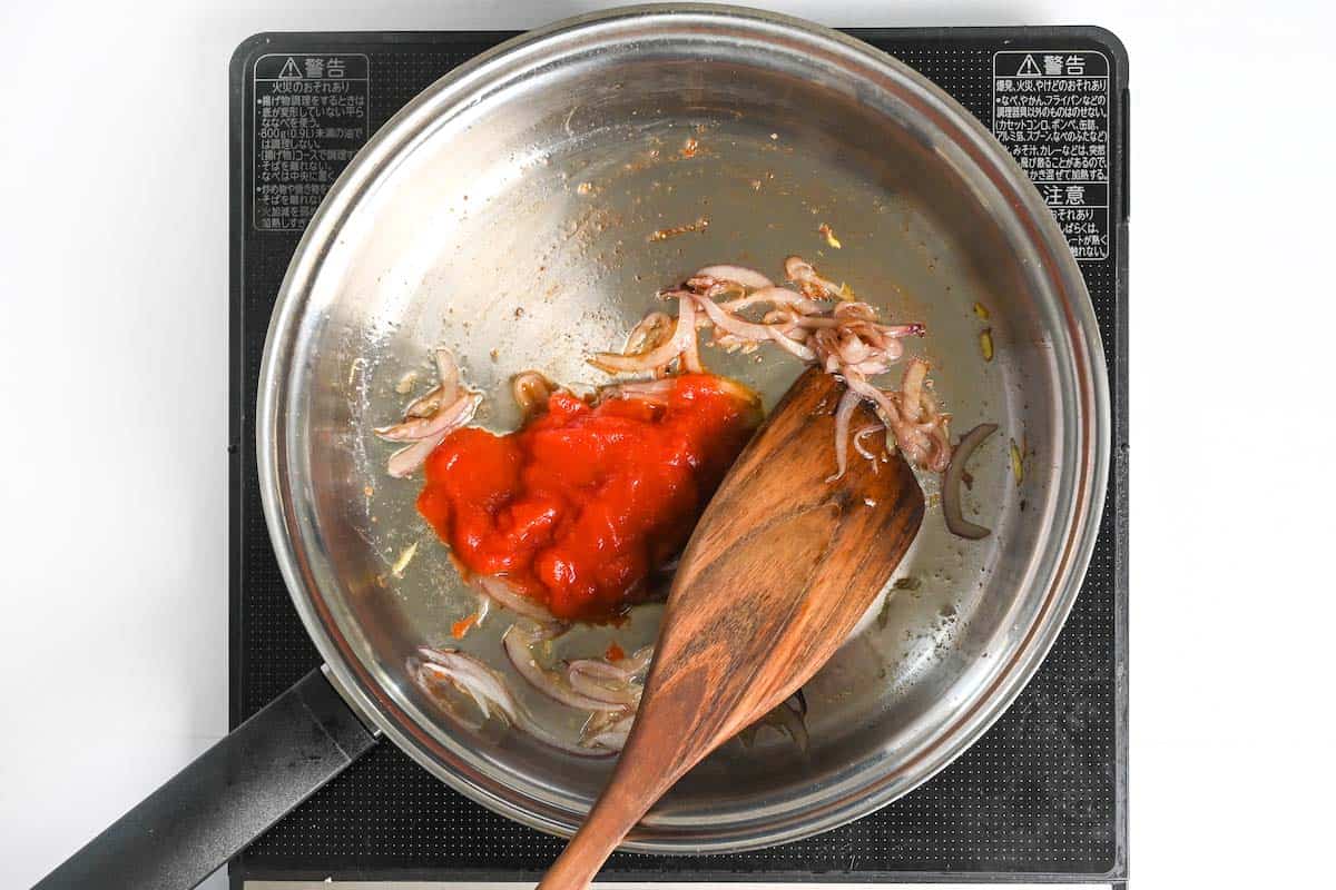 adding canned crushed tomatoes and white wine to the pan