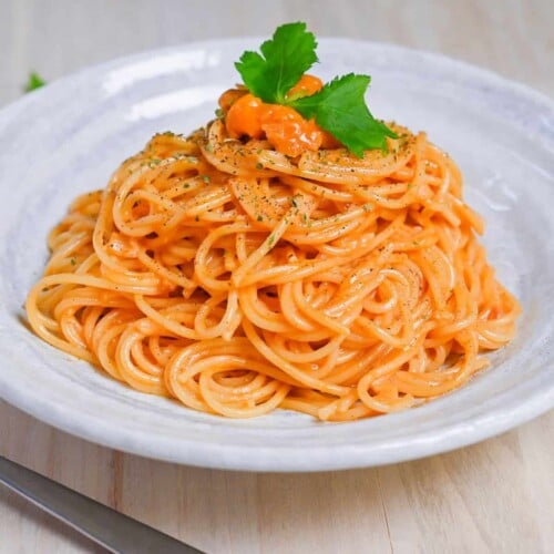 Japanese uni cream pasta served on a white plate and topped with black pepper and parsley