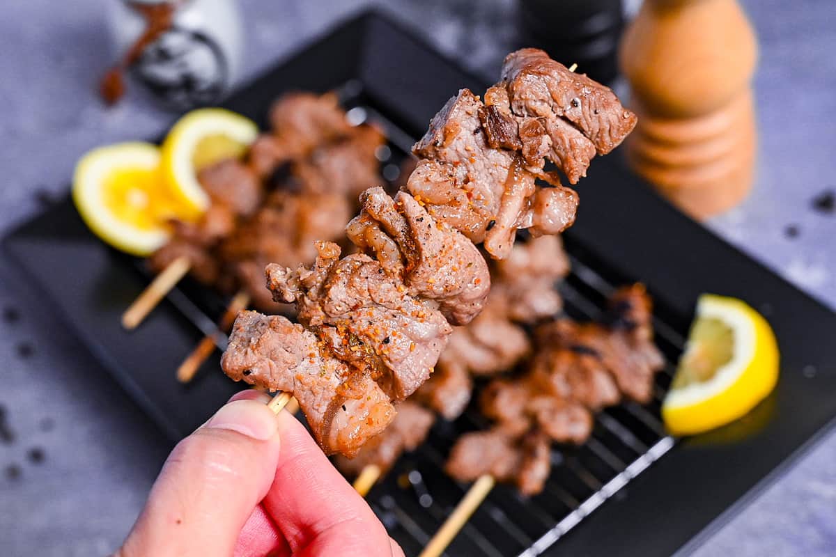 Beef Kushiyaki (Japanese Beef Skewers) served on a black rectangular plate with lemon wedges