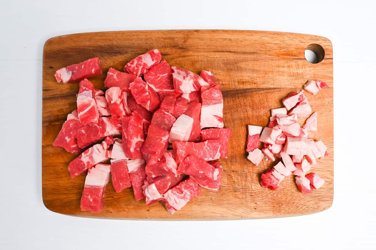 Beef steak cut into bitesize pieces on a wooden chopping board