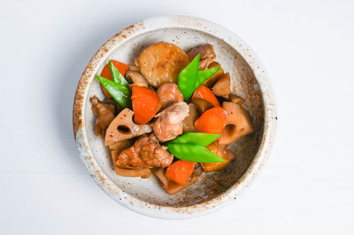 Final chikuzenni in a mottled beige bowl topped with blanched snow peas