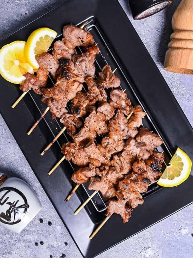 Beef Kushiyaki (Japanese Beef Skewers) served on a black rectangular plate with lemon wedges