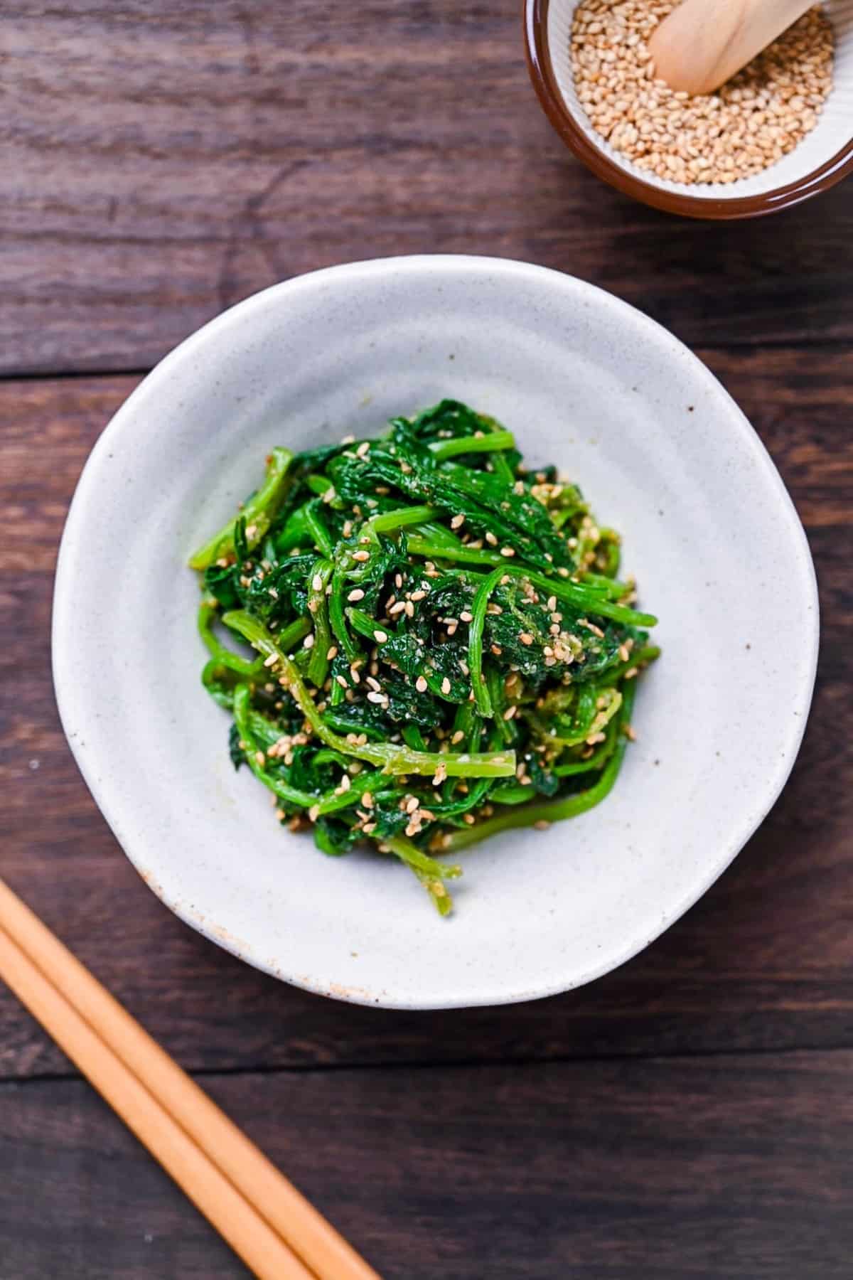 Japanese sesame spinach salad (horenso no goma-ae) on a white plate on a wooden surface