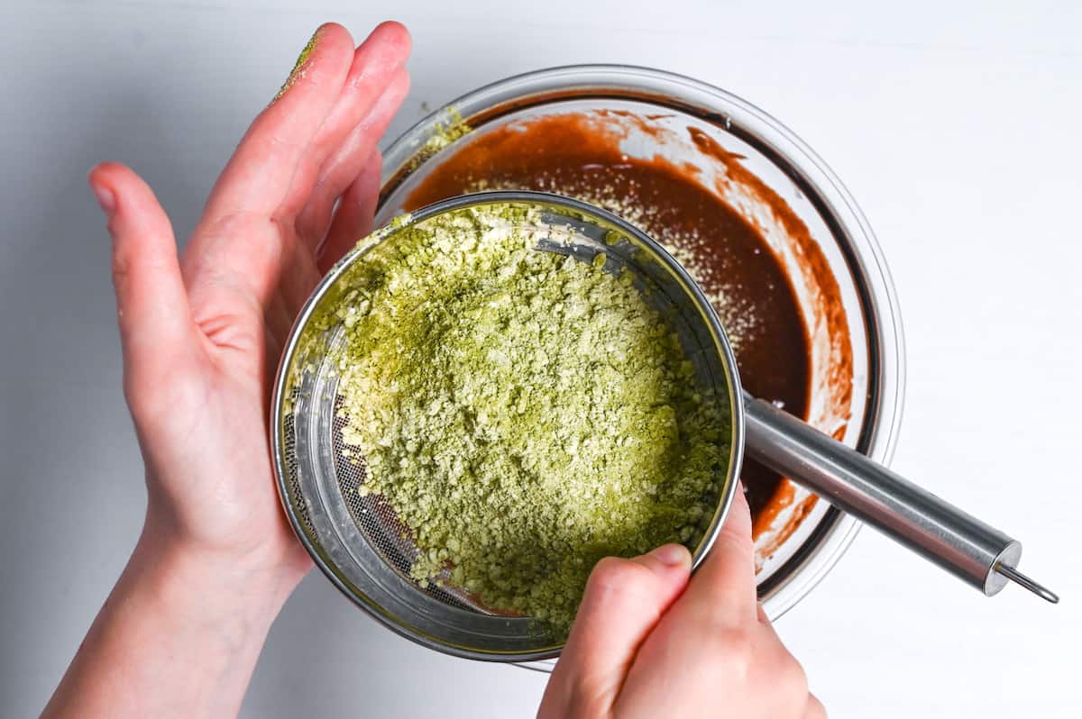 sifting flour and matcha into brownie mixture