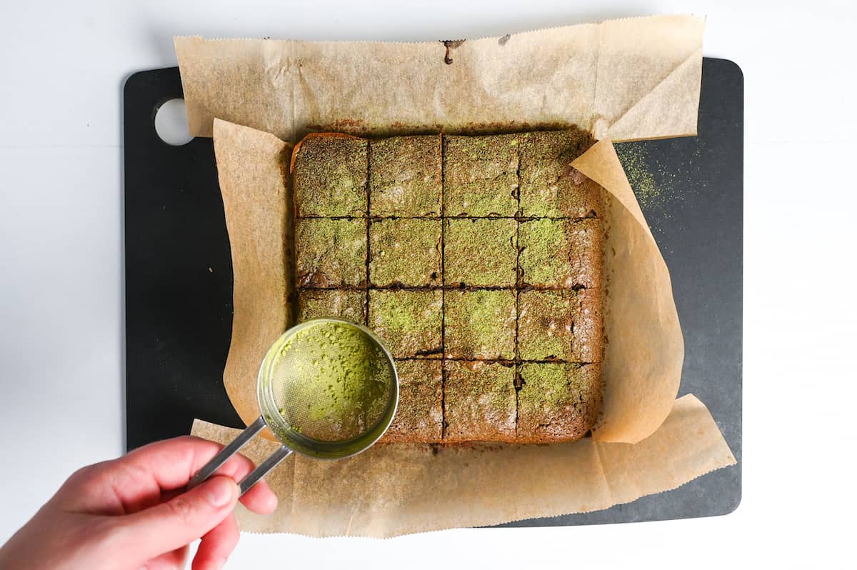 sprinkling the top of brownies with matcha powder