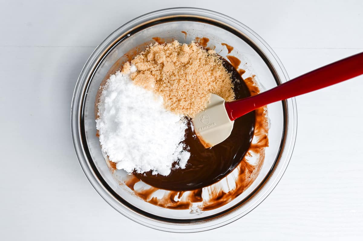 adding white sugar and light brown sugar to warm chocolate mixture