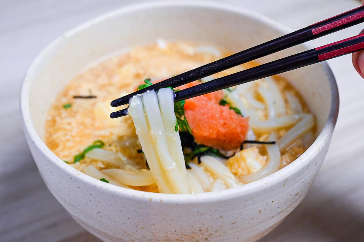 Holding mentaiko udon with black and red chopsticks