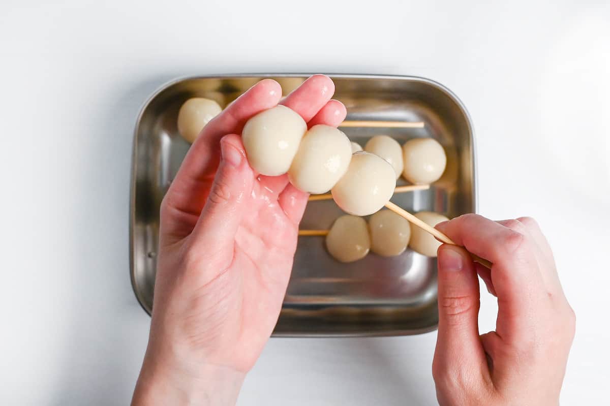 pushing dango onto a soaked skewer