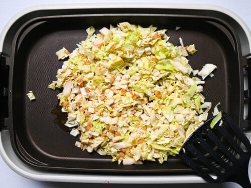 chopped cabbage on electric griddle with small amount of monjayaki sauce