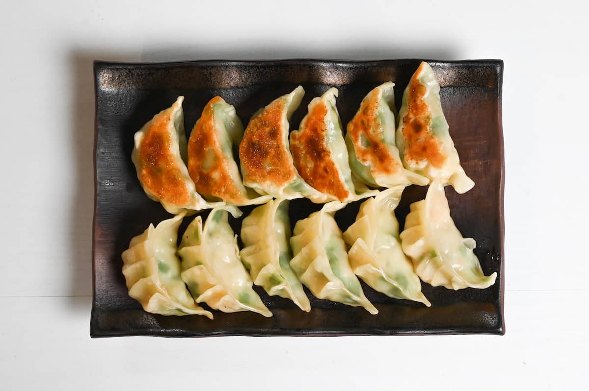 prawn gyoza arranged in rows on a brown rectangular plate