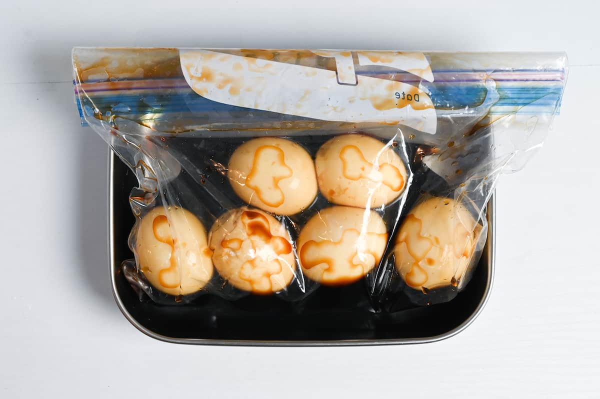 ramen eggs soaking in marinade in a ziplock bag in a metal tray