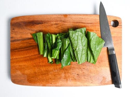 komatsuna cut into 5cm pieces on a wooden chopping board