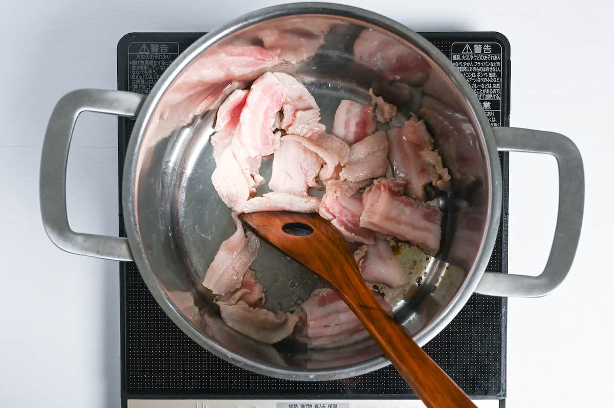 Frying sliced pork belly in a large pot