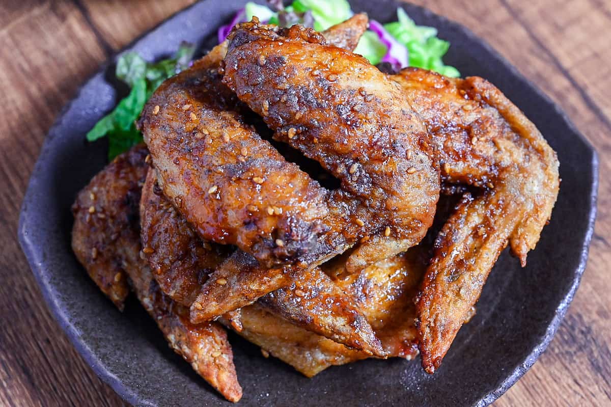 Yamachan Style Fried Chicken Wings (Nagoya Tebasaki) stacked on a dark plate with salad