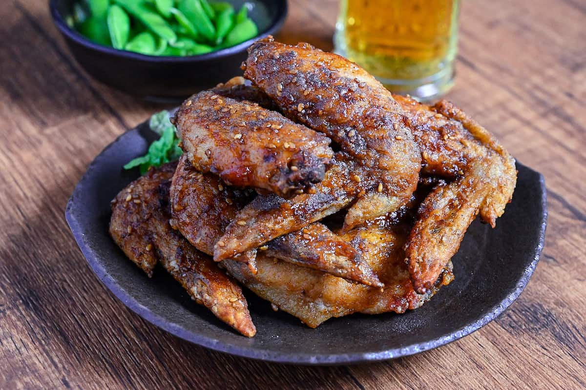 Yamachan Style Fried Chicken Wings (Nagoya Tebasaki) stacked on a dark plate with salad