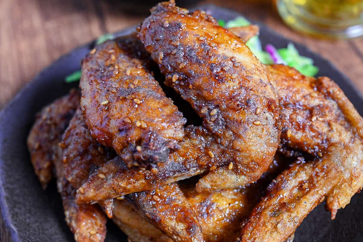 Yamachan Style Fried Chicken Wings (Nagoya Tebasaki) stacked on a dark plate with salad close up