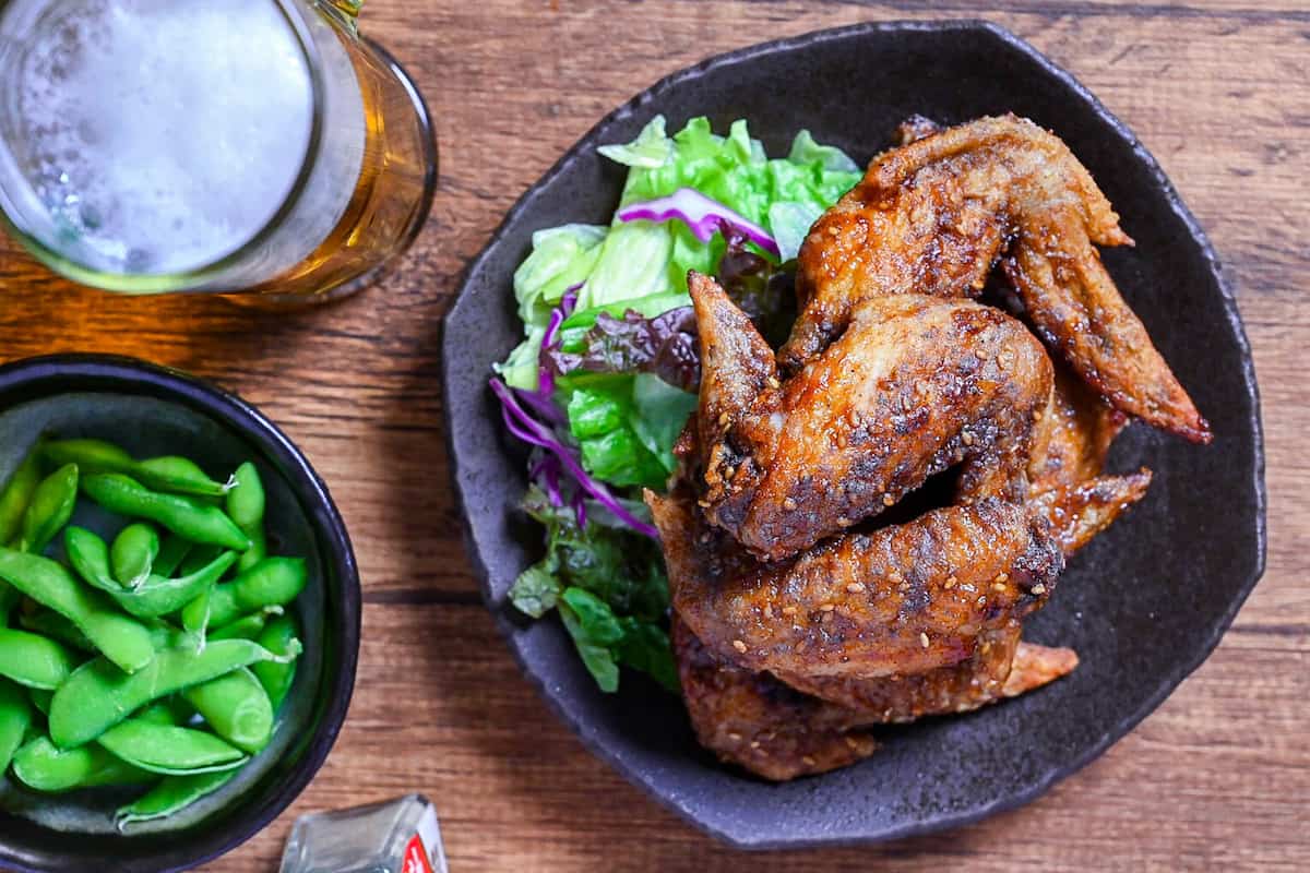 Yamachan Style Fried Chicken Wings (Nagoya Tebasaki) stacked on a dark plate with salad top down