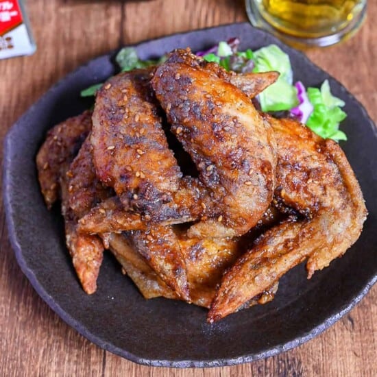 Yamachan Style Fried Chicken Wings (Nagoya Tebasaki) stacked on a dark plate with salad