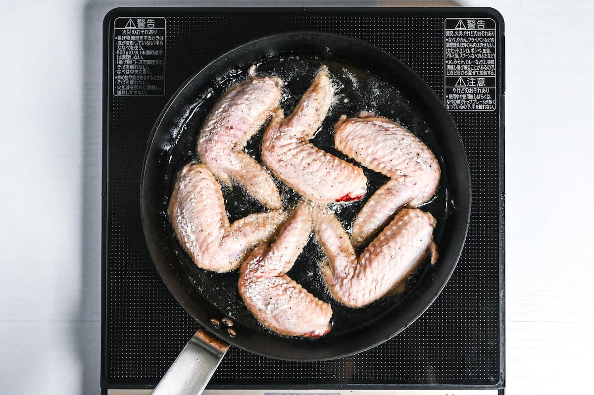 chicken wings shallow frying in a pan