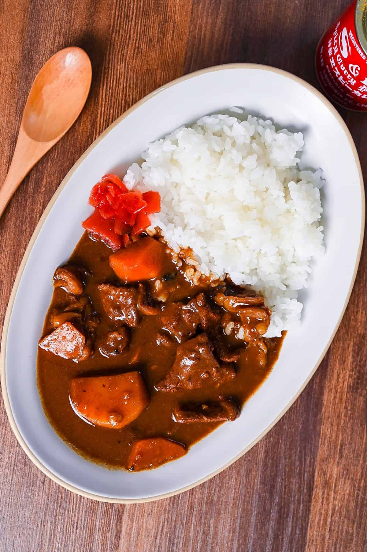 Homemade Japanese beef curry rice from scratch served on a white oval plate with fukujinzuke pickles