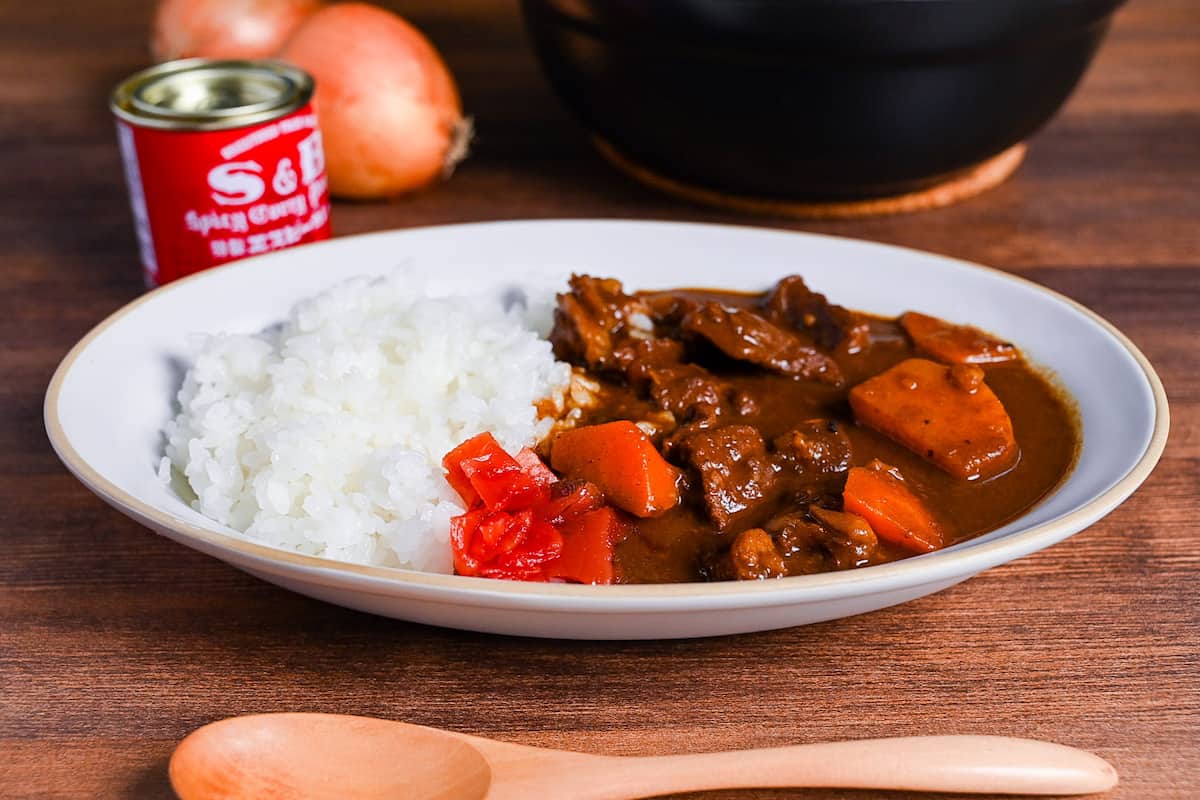 Homemade Japanese beef curry rice from scratch served on a white oval plate with fukujinzuke pickles