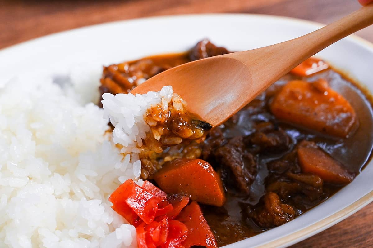 Homemade Japanese beef curry rice from scratch served on a white oval plate with fukujinzuke pickles