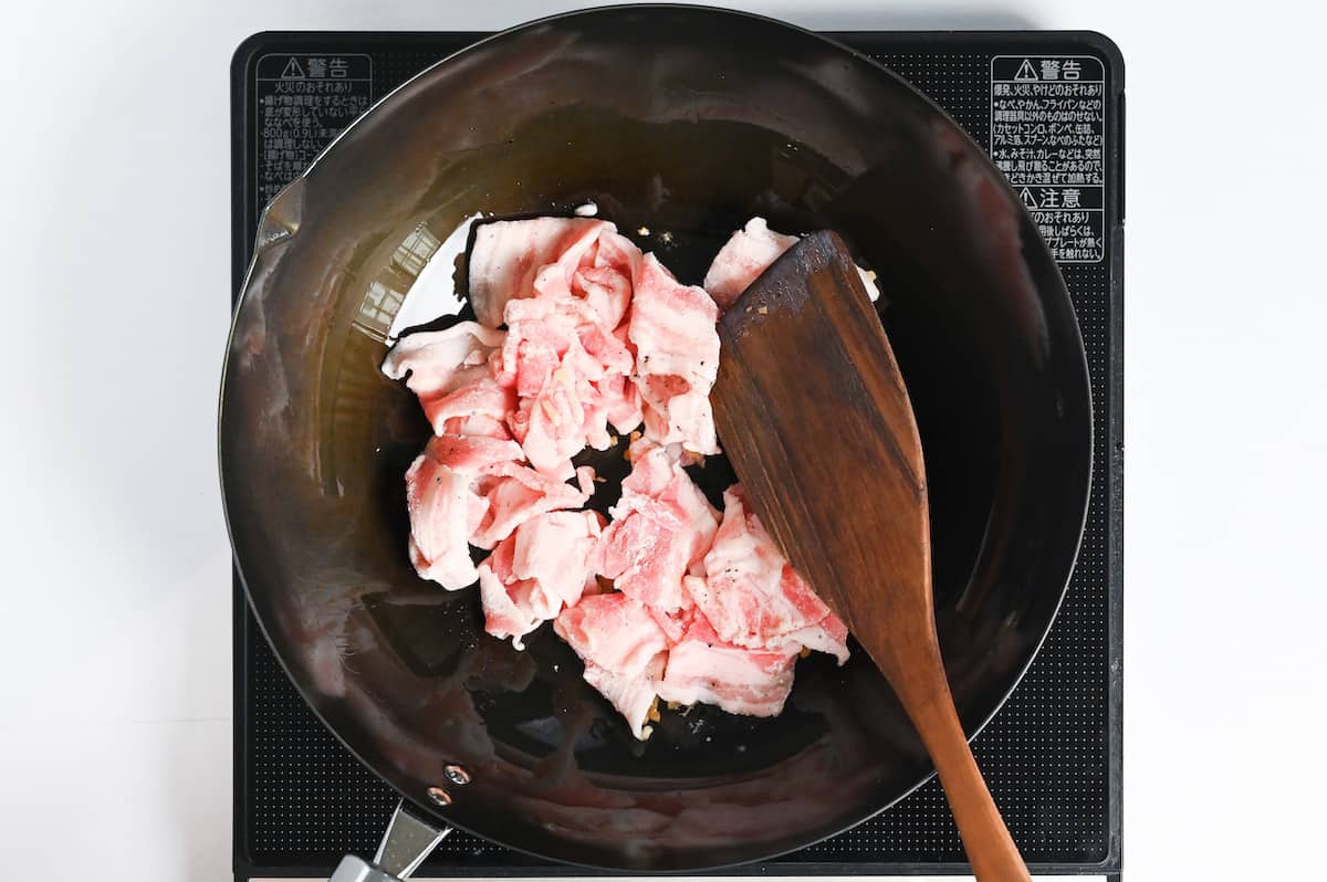 thinly sliced pork belly frying in a wok