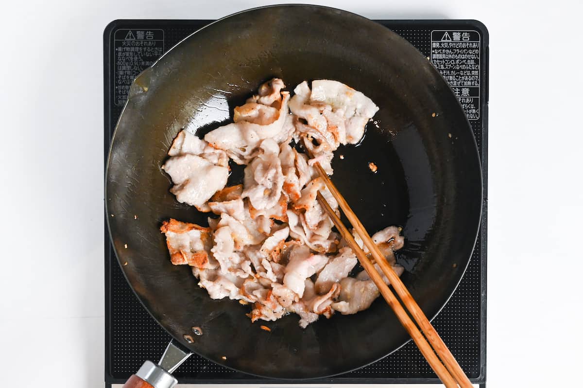 thinly sliced pork belly frying in a wok