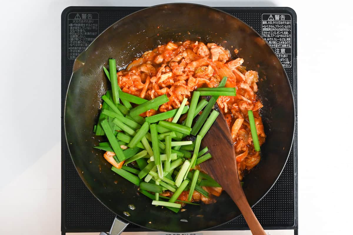 Adding chopped garlic chives to buta kimchi