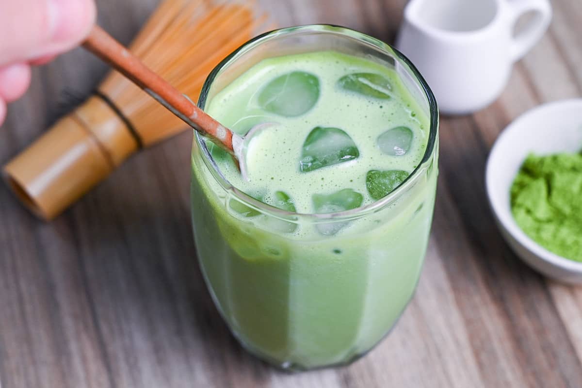 mixing iced matcha latte with small spoon