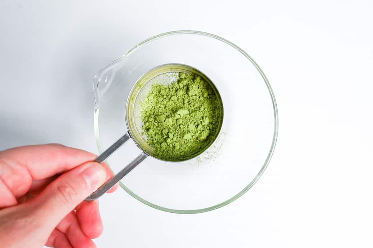 sifting matcha into a glass bowl