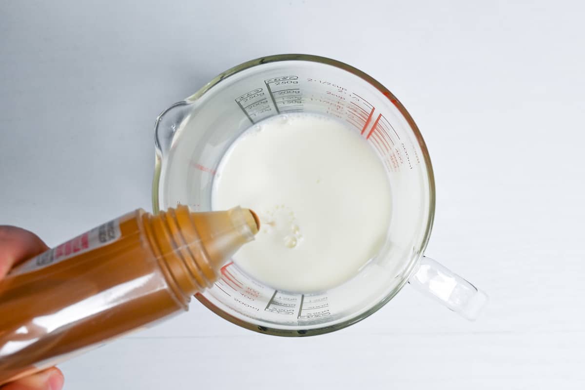 pouring honey into milk in a glass measuring jug