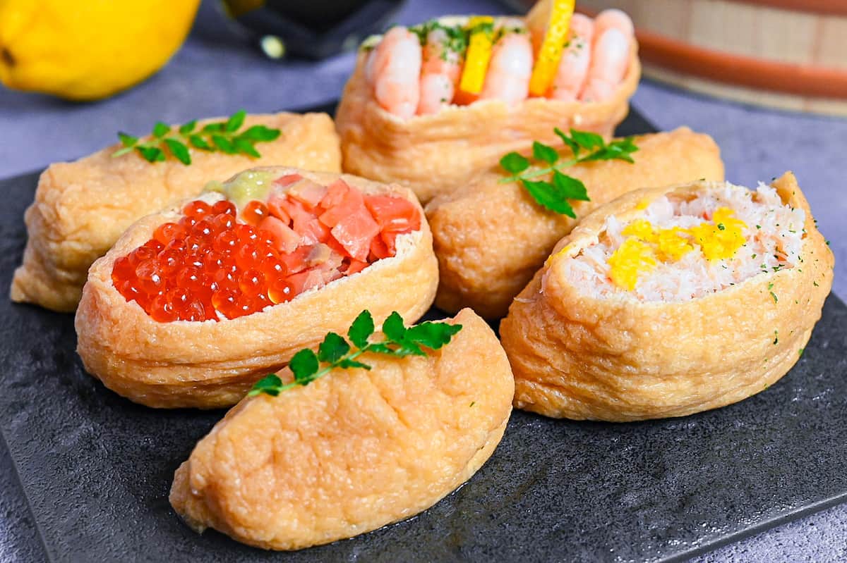 Inarizushi (inari sushi/ stuffed tofu touches) with various toppings on a slate style square plate