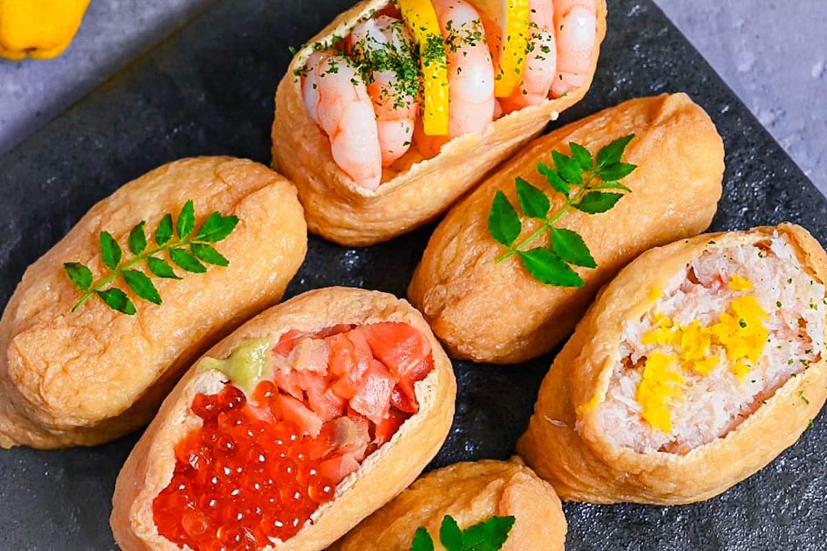 Inarizushi (inari sushi/ stuffed tofu touches) with various toppings on a slate style square plate