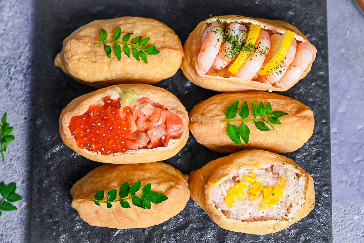 Inarizushi (inari sushi/ stuffed tofu touches) with various toppings on a slate style square plate