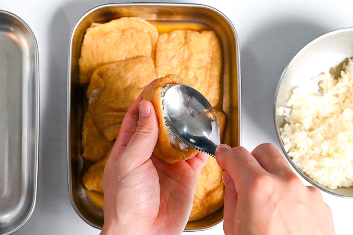 pressing rice into fried tofu pouch with back of a spoon