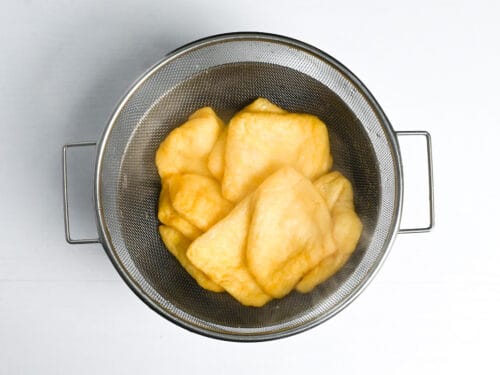 Draining aburaage (fried tofu pouches) in a mesh sieve