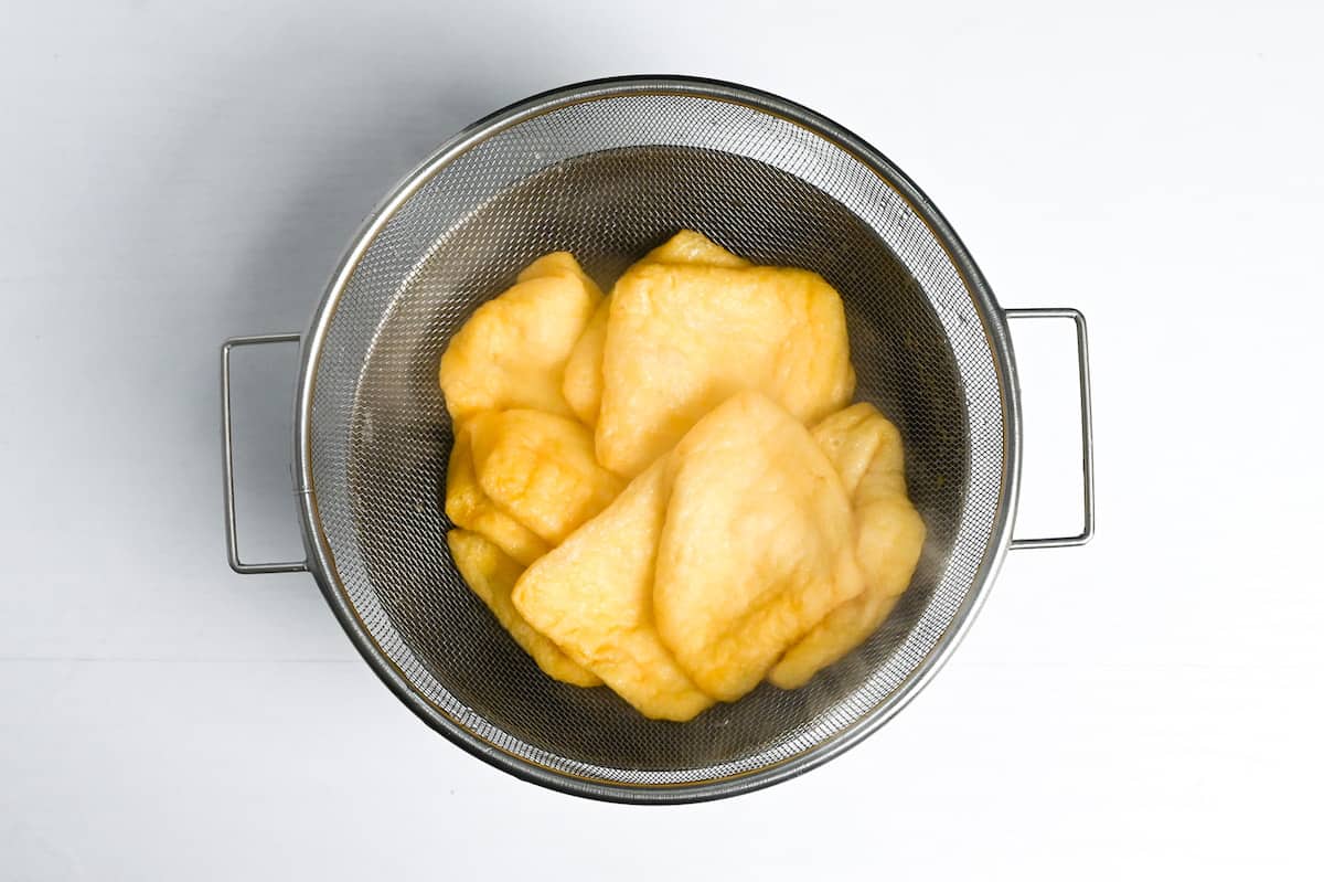Draining aburaage (fried tofu pouches) in a mesh sieve