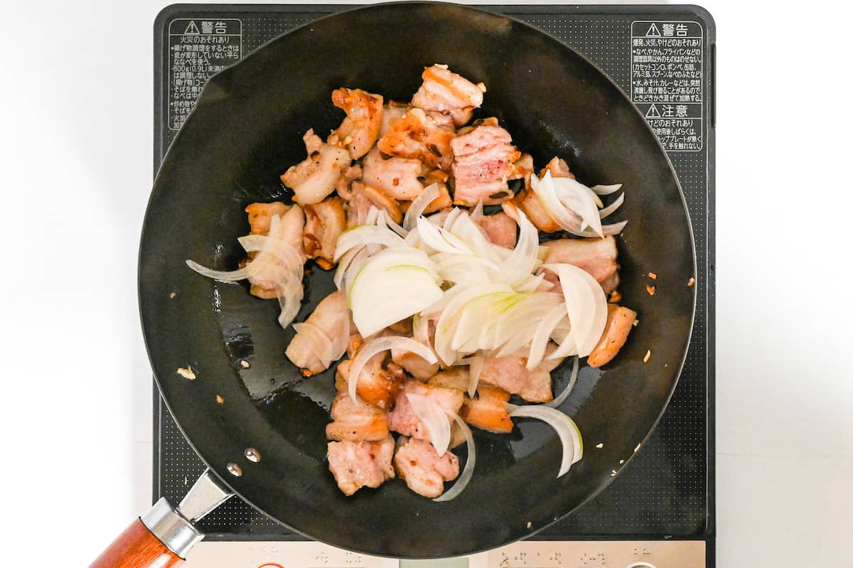 stir-frying pork and onions in a wok