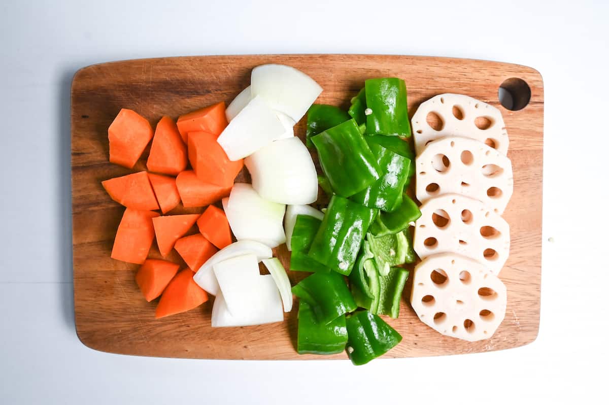 carrot, onion, green bell pepper and lotus root on a wooden chopping board