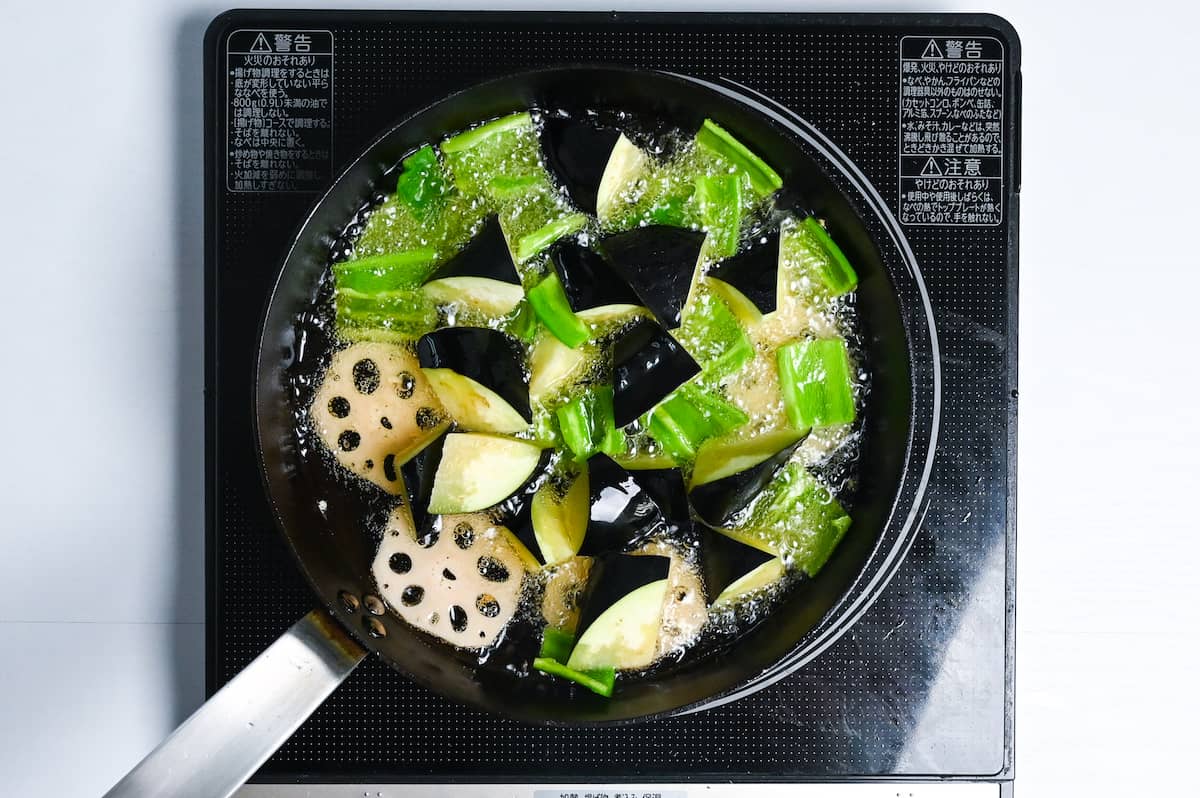 eggplant, bell peppers and lotus root shallow frying in a pan