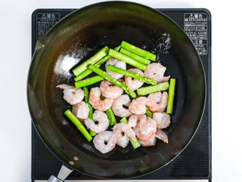 shrimp and asparagus frying in a wok