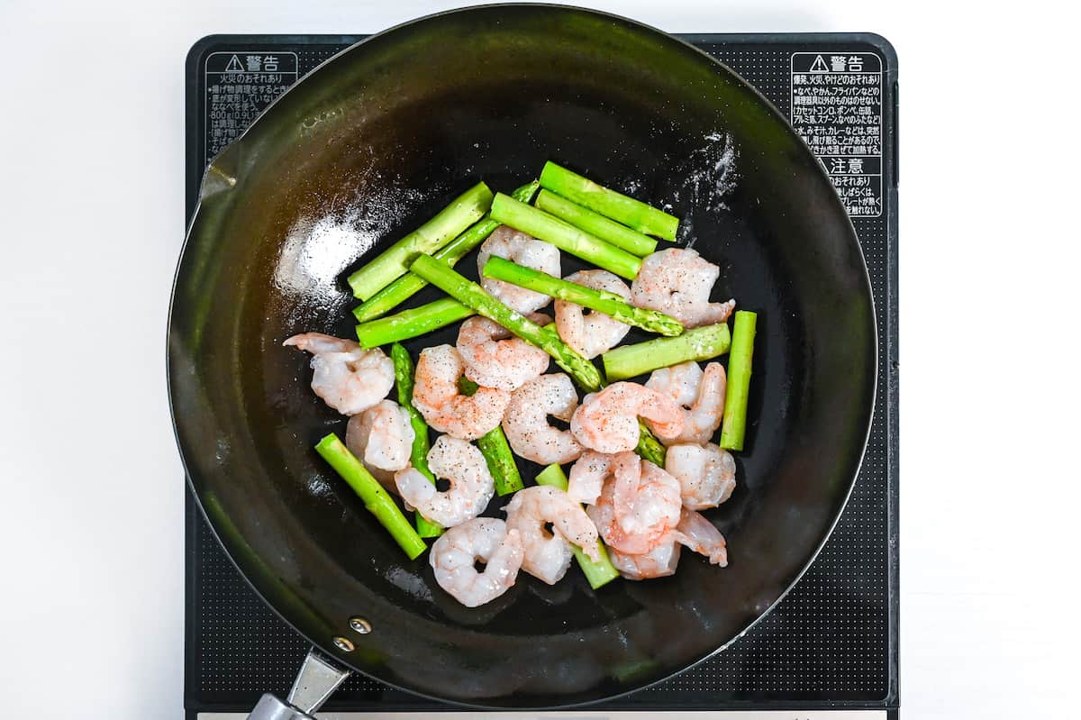 shrimp and asparagus frying in a wok
