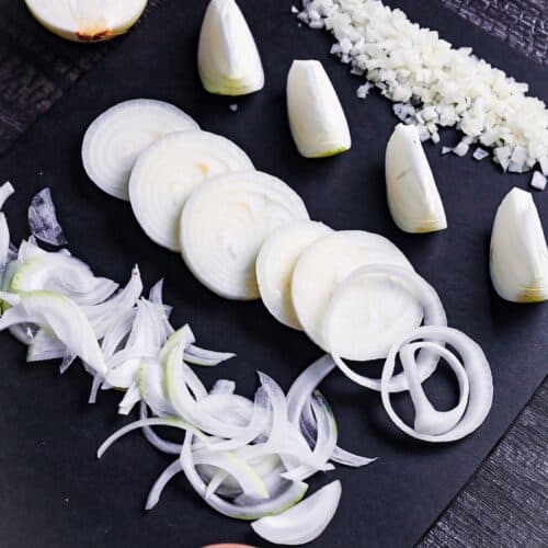 onions cut in 4 different ways on a black chopping board