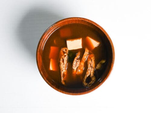 completed aka-dashi (red miso soup) made with wakame, fried tofu pouch and firm tofu in a wooden bowl