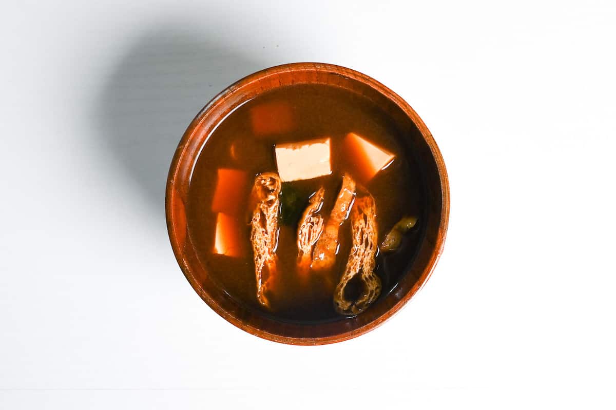 completed aka-dashi (red miso soup) made with wakame, fried tofu pouch and firm tofu in a wooden bowl