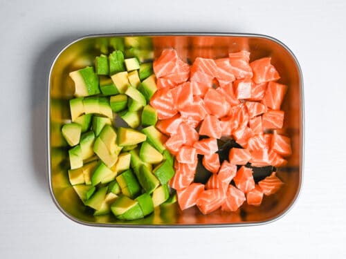 cubed avocado and sashimi grade salmon in a container with a piece of kombu