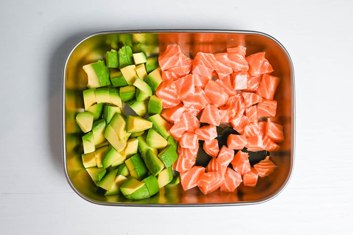 cubed avocado and sashimi grade salmon in a container with a piece of kombu
